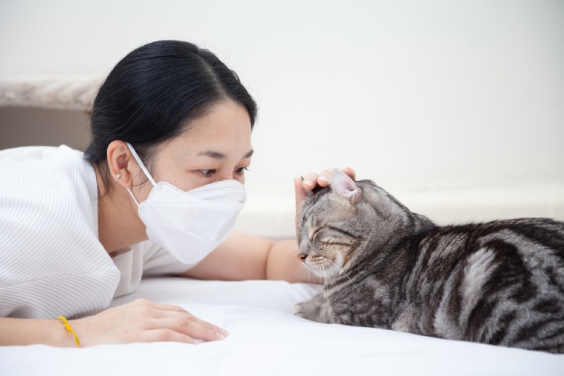 cat owner wearing a mask with her pet cat at home